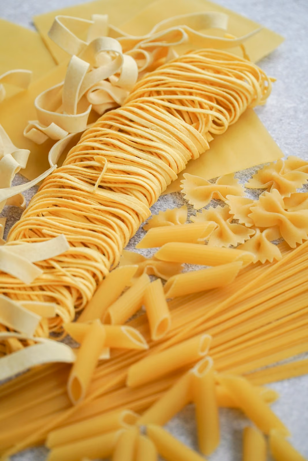 Verschiedene Pastasorten auf gelbem Grund